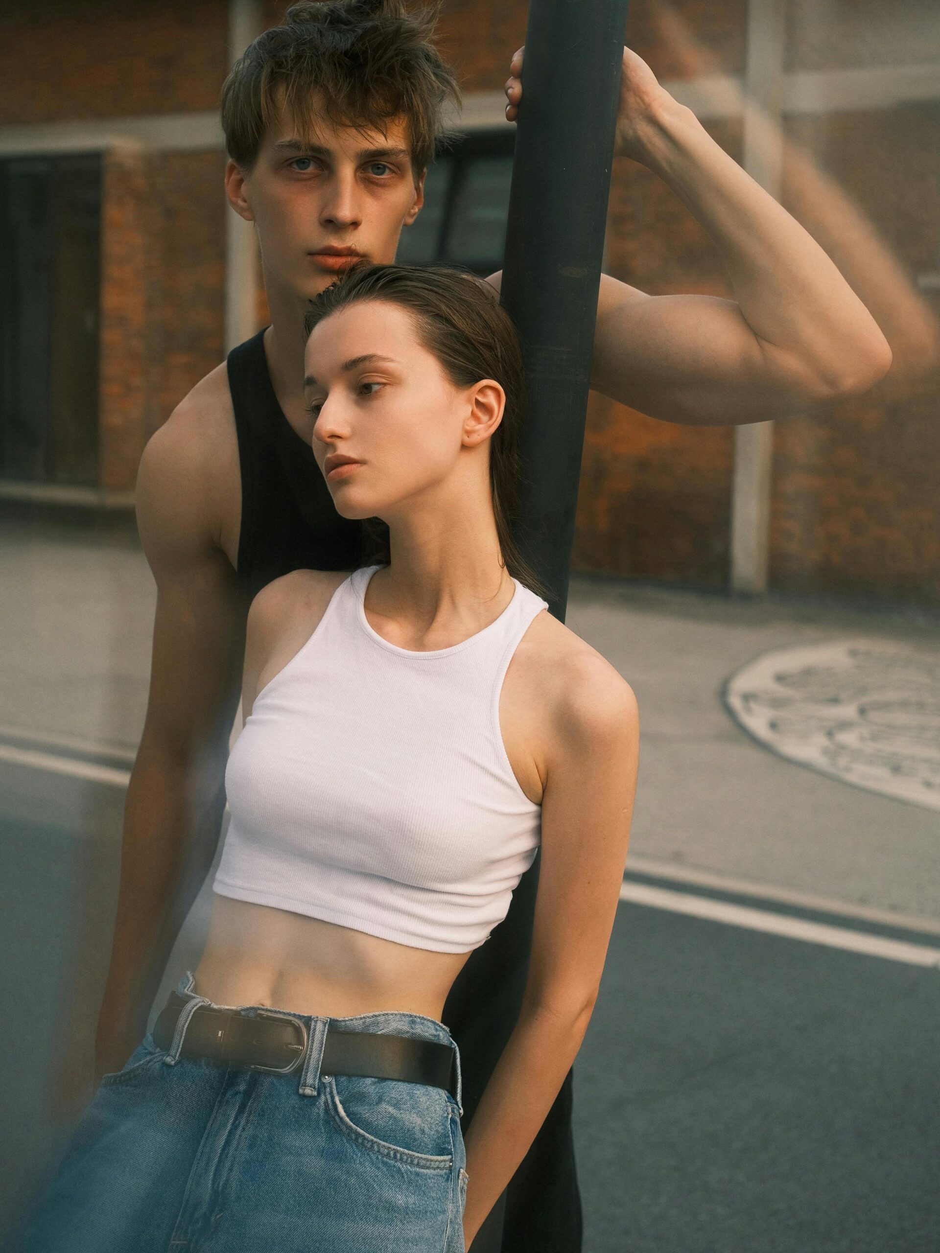 A fashionable young couple posing outdoors, showcasing urban style in casual clothing.